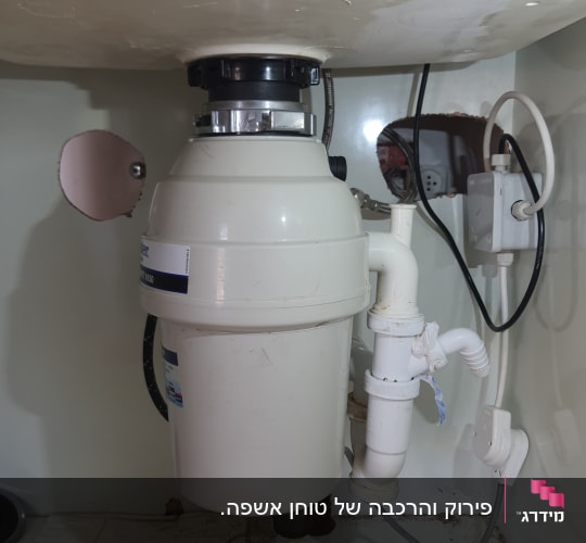 מתקן טוחן אשפה מתחת לכיור עם צינורות חיבור